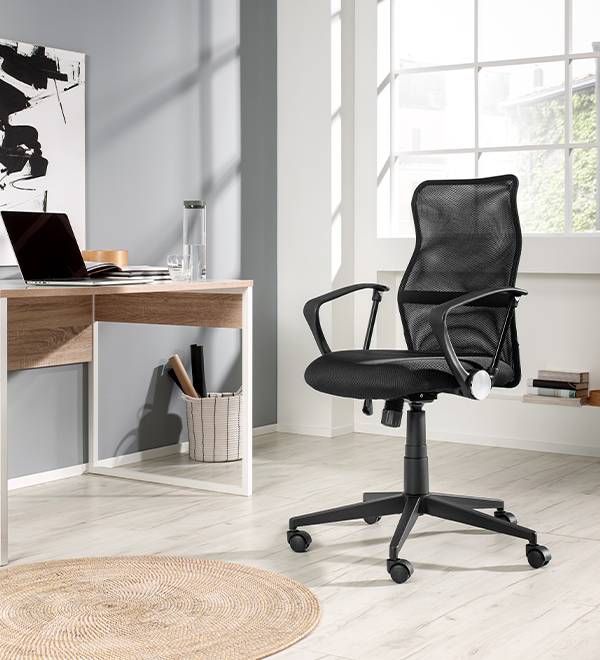 Black mesh office chair in a modern home office with a light wood desk.