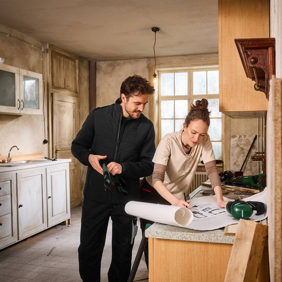 Man and woman in workwear planning a kitchen renovation.