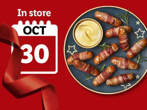 Pigs in blankets with mustard on a plate, with a calendar showing 'OCT 30' and a red ribbon.