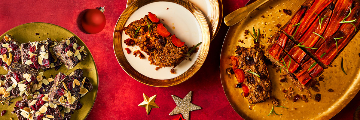 Christmas vegan desserts on golden plates, with festive decorations on a red background.
