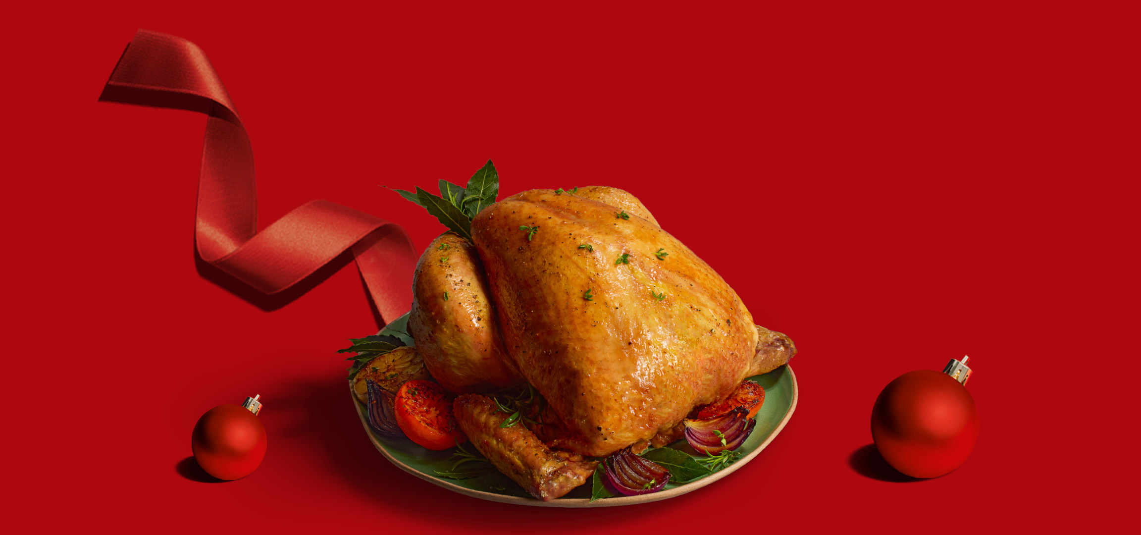 Roasted chicken with vegetables and Christmas ornaments on a red background.