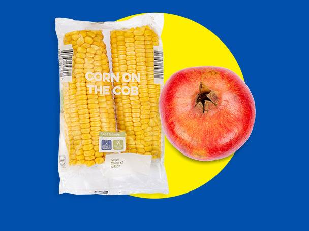 Packaged corn on the cob and a pomegranate on a blue and yellow background.