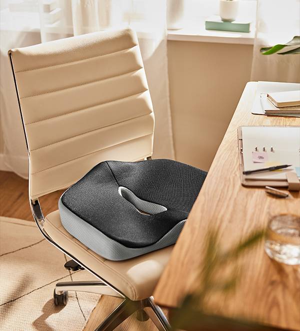 Ergonomic seat cushion on a beige office chair at a wooden desk.