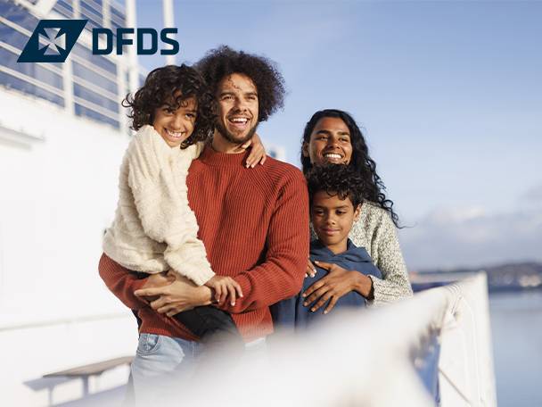 A family of four, two adults and two children, smiling on a ferry deck.