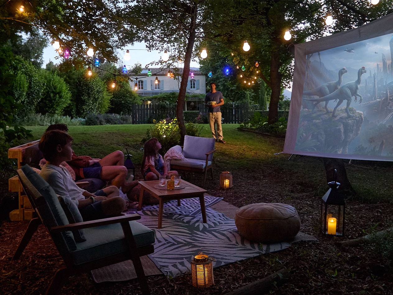 Family enjoying an outdoor movie night with string lights and comfortable garden furniture.