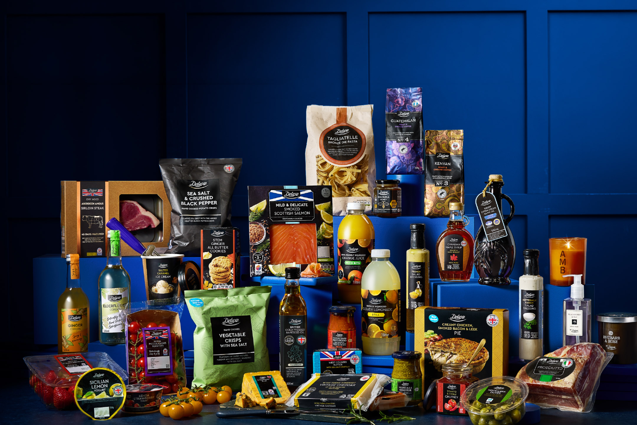 A premium selection of food and drink products arranged on a blue background.