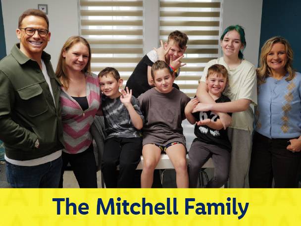 The Mitchell Family, a large family with two adults and seven children, smiling at the camera.