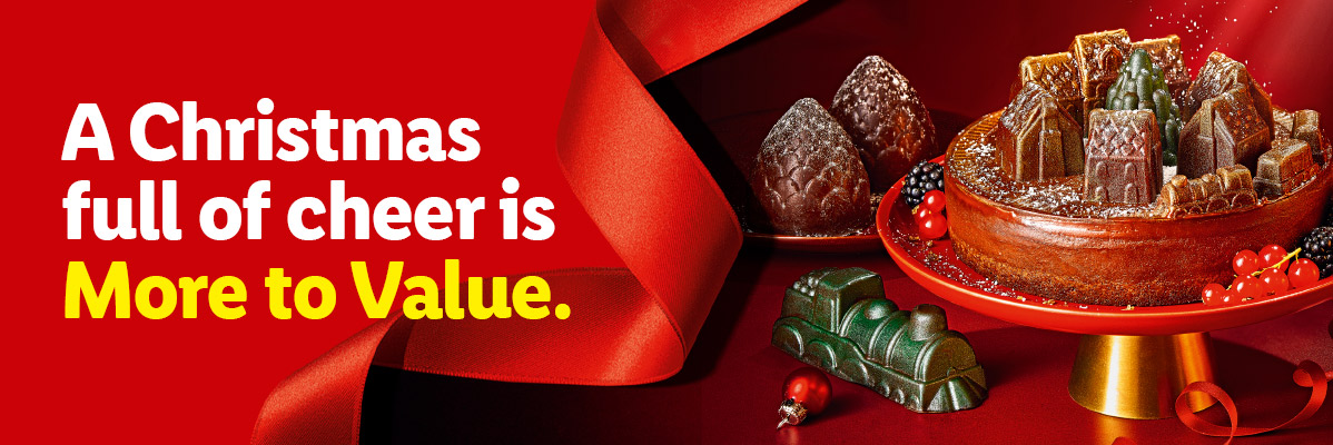 Christmas cake with festive gummy decorations, berries, and a red ribbon, with text: 'A Christmas full of cheer is More to Value.'