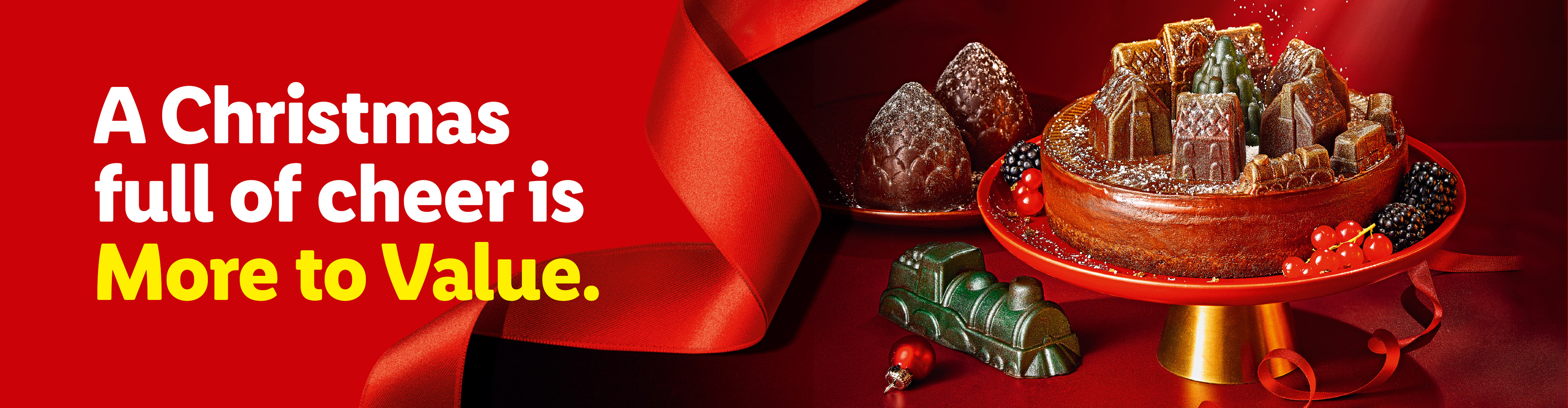 Christmas cake with festive gummy decorations, berries, and a red ribbon, with text: 'A Christmas full of cheer is More to Value.'