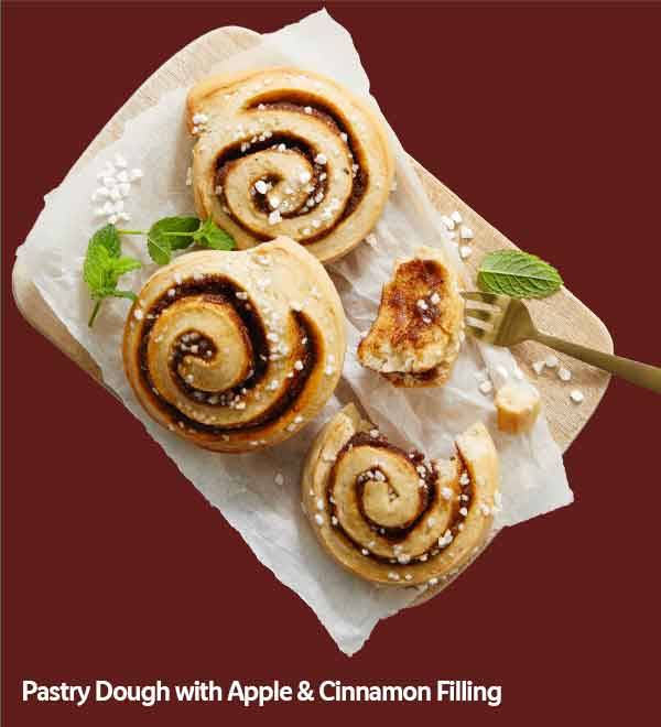 Three cinnamon rolls with apple filling, one partially eaten, on a wooden board.