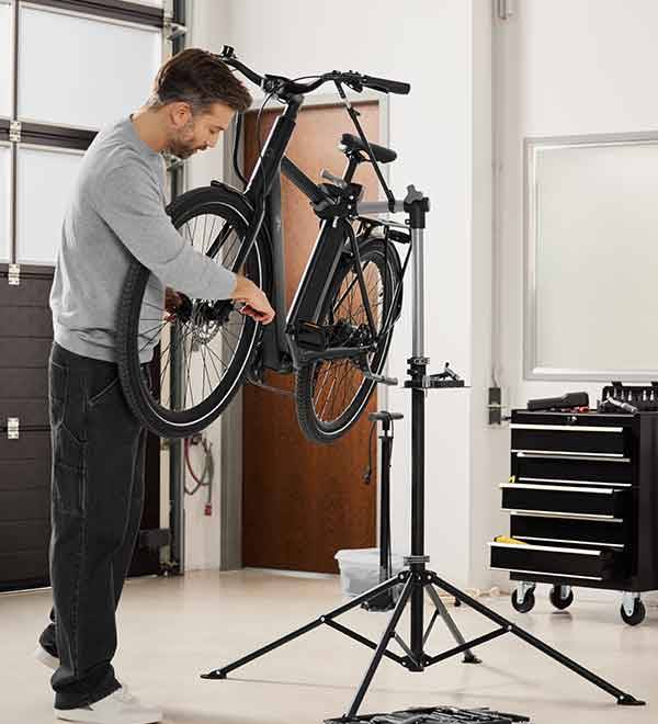 A man repairs an e-bike on a Park Tool bicycle repair stand in a workshop.