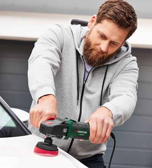 A man uses a Parkside polisher to buff a car.