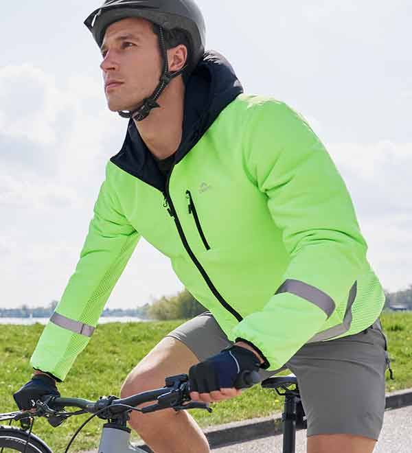 A man cycles wearing a bright green Crivit cycling jacket and helmet.