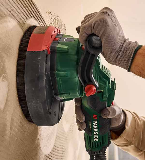 A person uses a Parkside wall sander to smooth a textured wall surface.