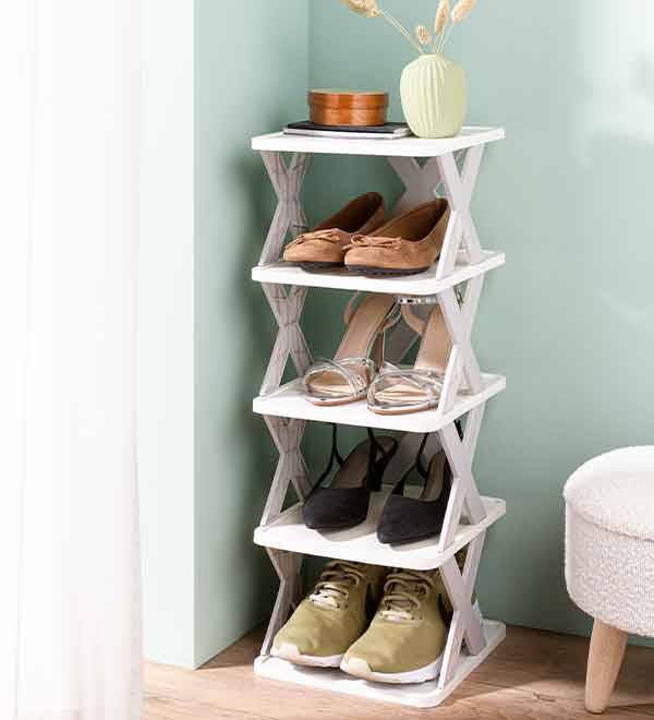 A white shoe rack with five shelves holding various pairs of shoes, including flats, heels, and sneakers.