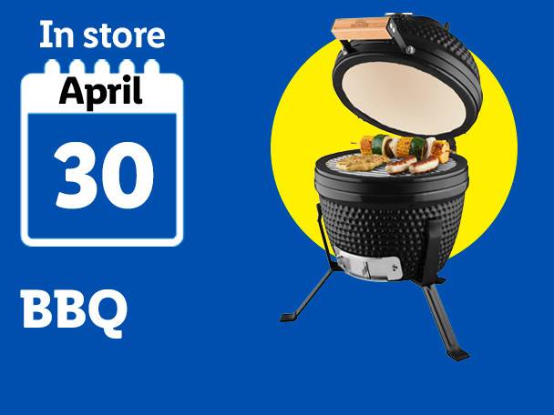Black ceramic BBQ grill with food on it, available in store April 30th.