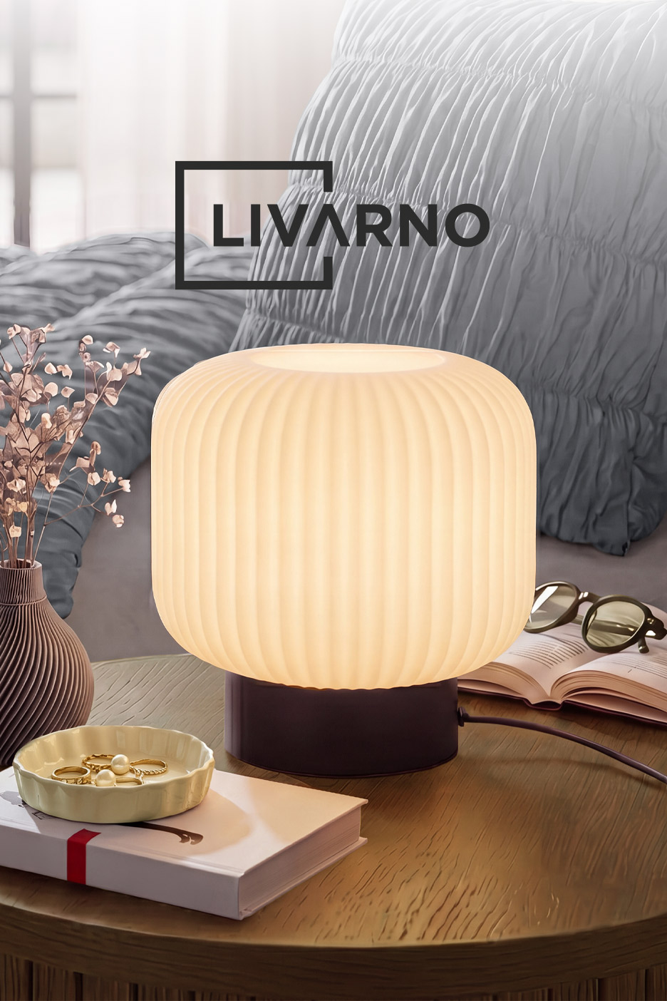 A ribbed glass table lamp glowing warmly on a wooden bedside table.