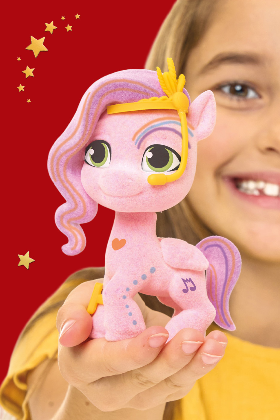 A child holding a pink, flocked toy pony with a yellow headset and musical note symbol.