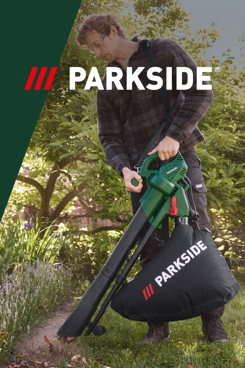 A man using an electric leaf blower and vacuum to clear leaves in a garden.