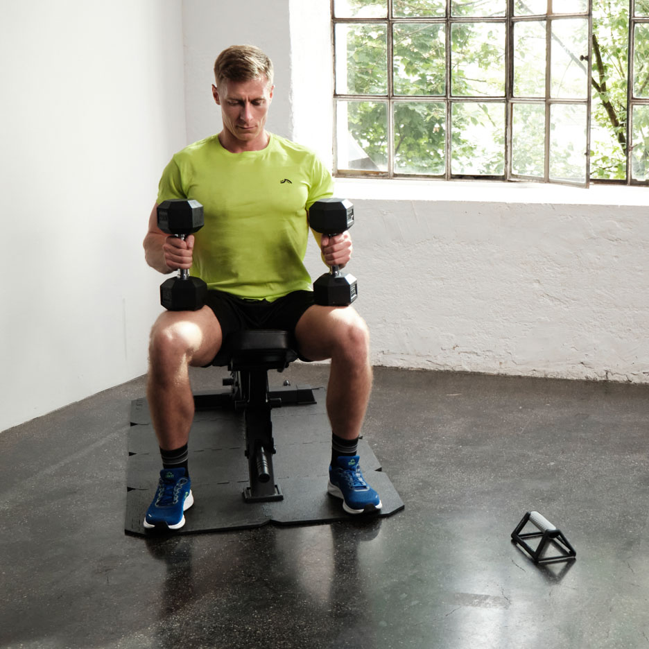 Man exercising with dumbbells on a bench.