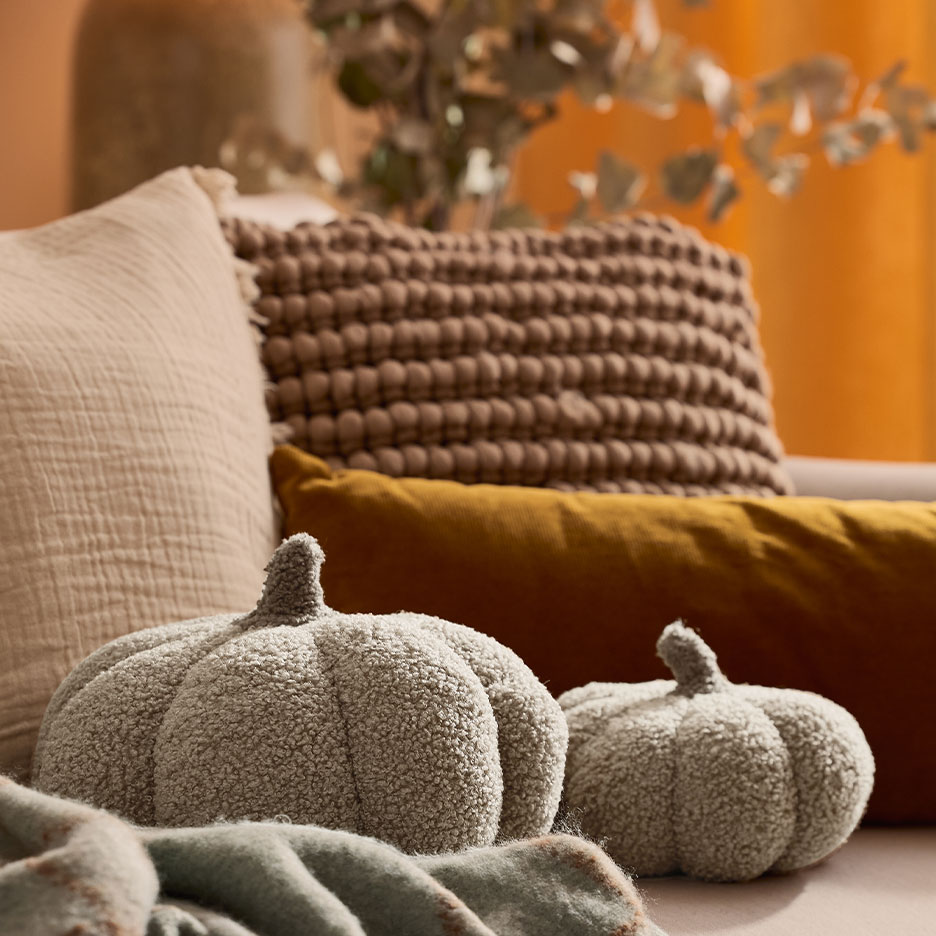 Cozy sofa with decorative pillows and two soft pumpkin-shaped cushions.