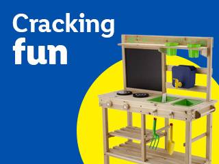 Cracking fun: Wooden outdoor mud kitchen with chalkboard, sink, and accessories on a blue and yellow background.