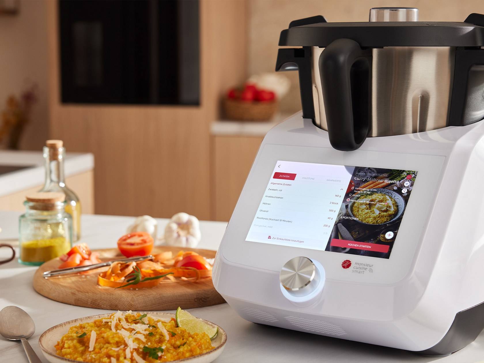 A Monsieur Cuisine Smart food processor displaying a curry carrot risotto recipe in a kitchen.