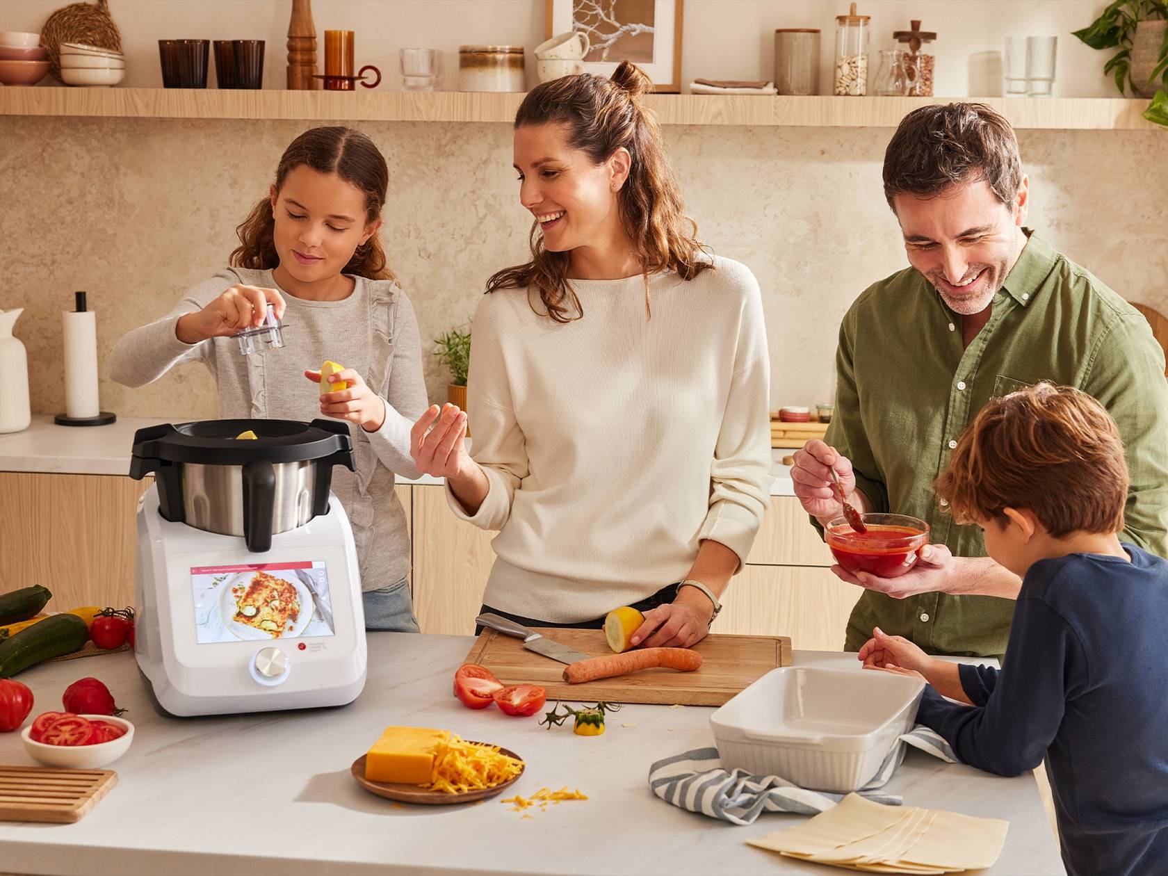 A family cooking together in a kitchen, with a smart cooking appliance on the counter.