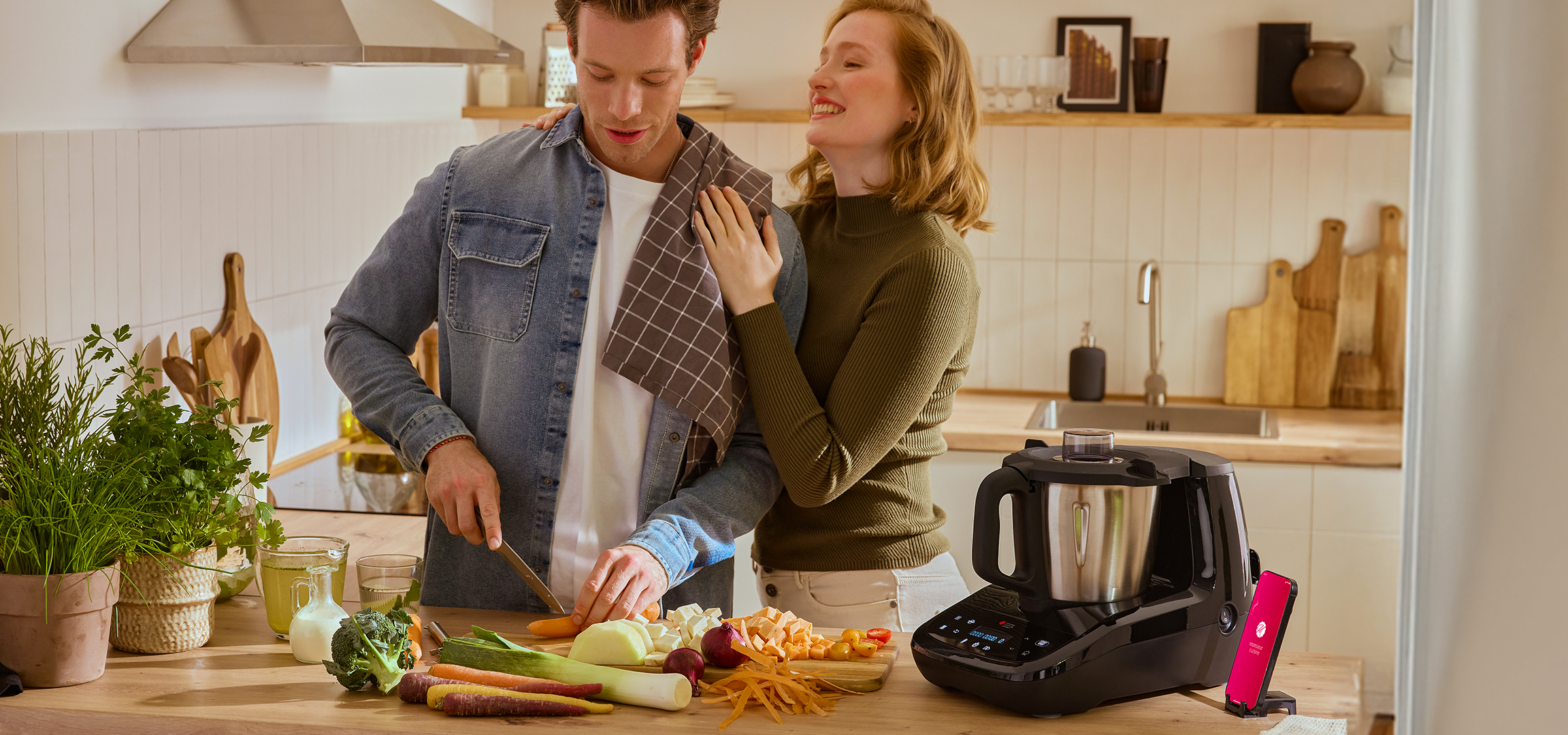 Couple chopping vegetables in kitchen with Monsieur Cuisine food processor.