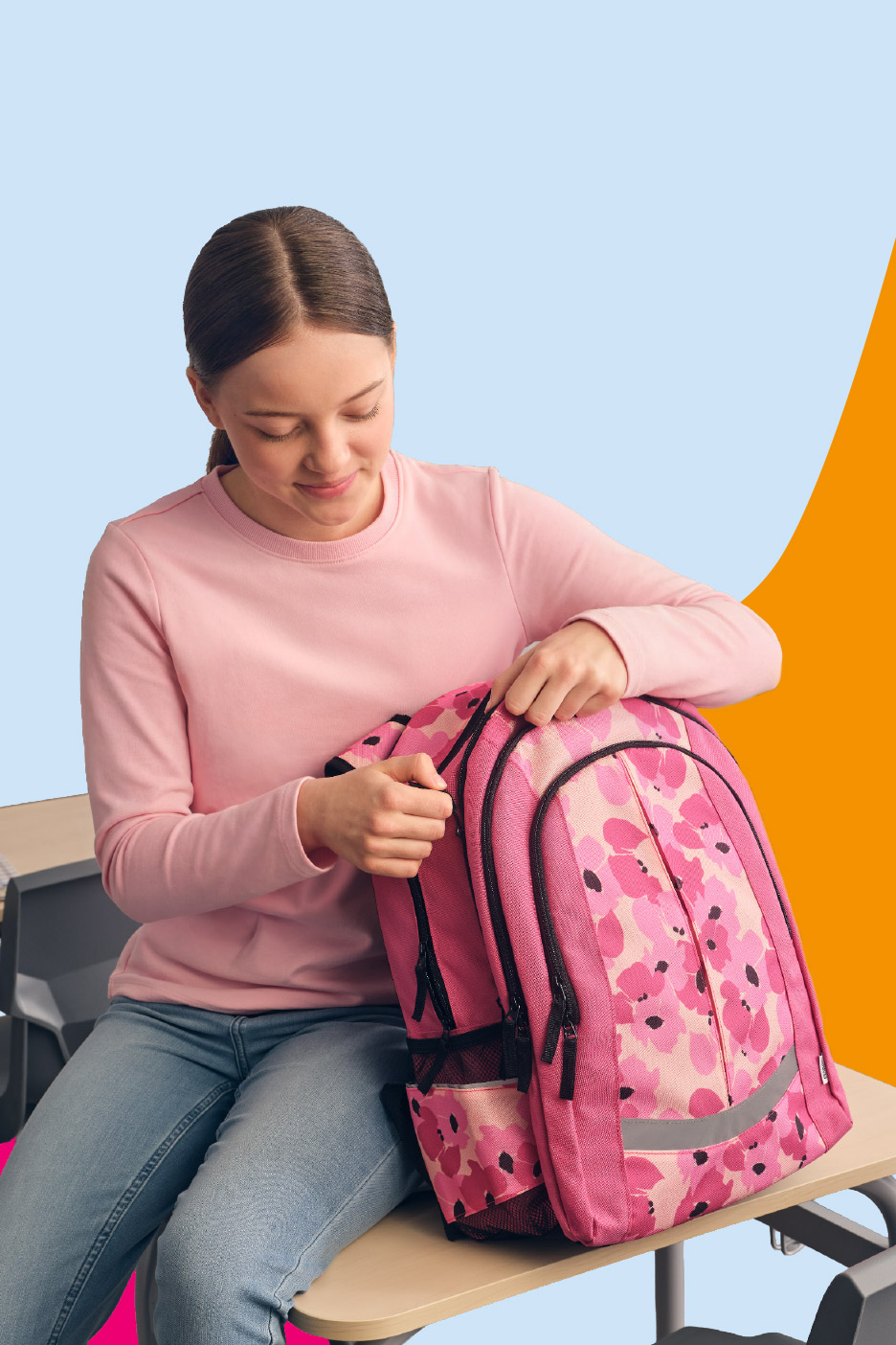 Girl in a pink sweatshirt and jeans, opening a pink floral backpack.