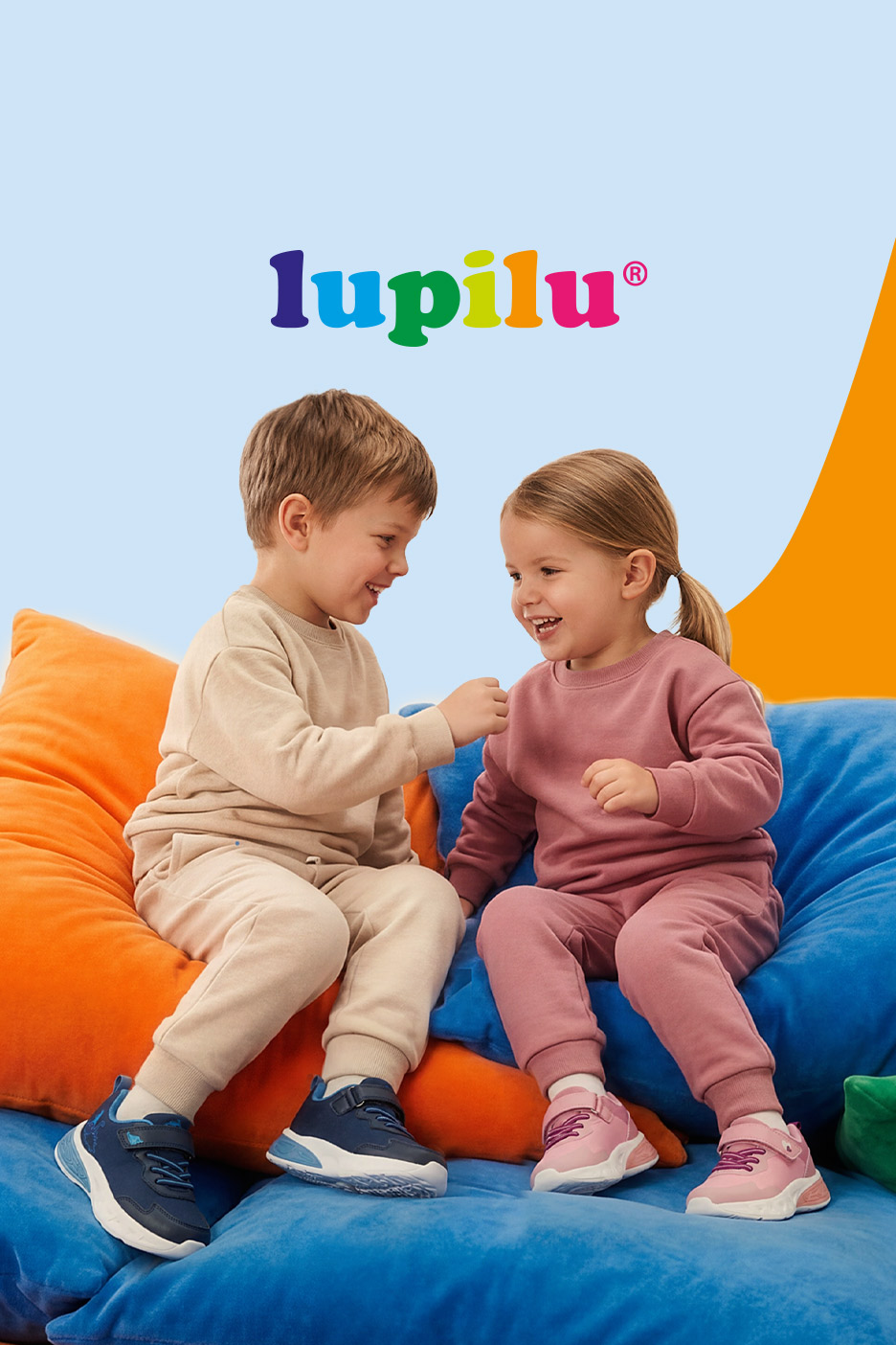 Two happy children in tracksuits and sneakers, sitting on colorful bean bags.