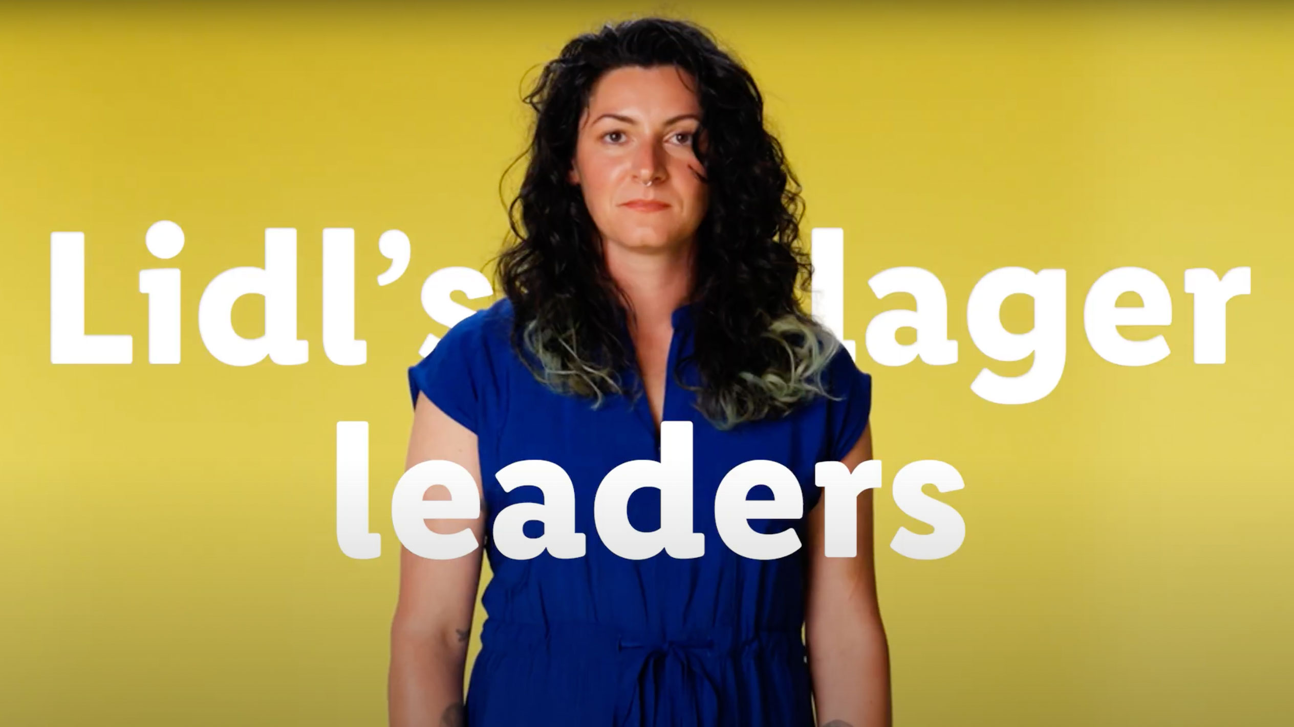 A woman in a blue dress stands in front of a yellow background with the words 'Lidl's lager leaders'.