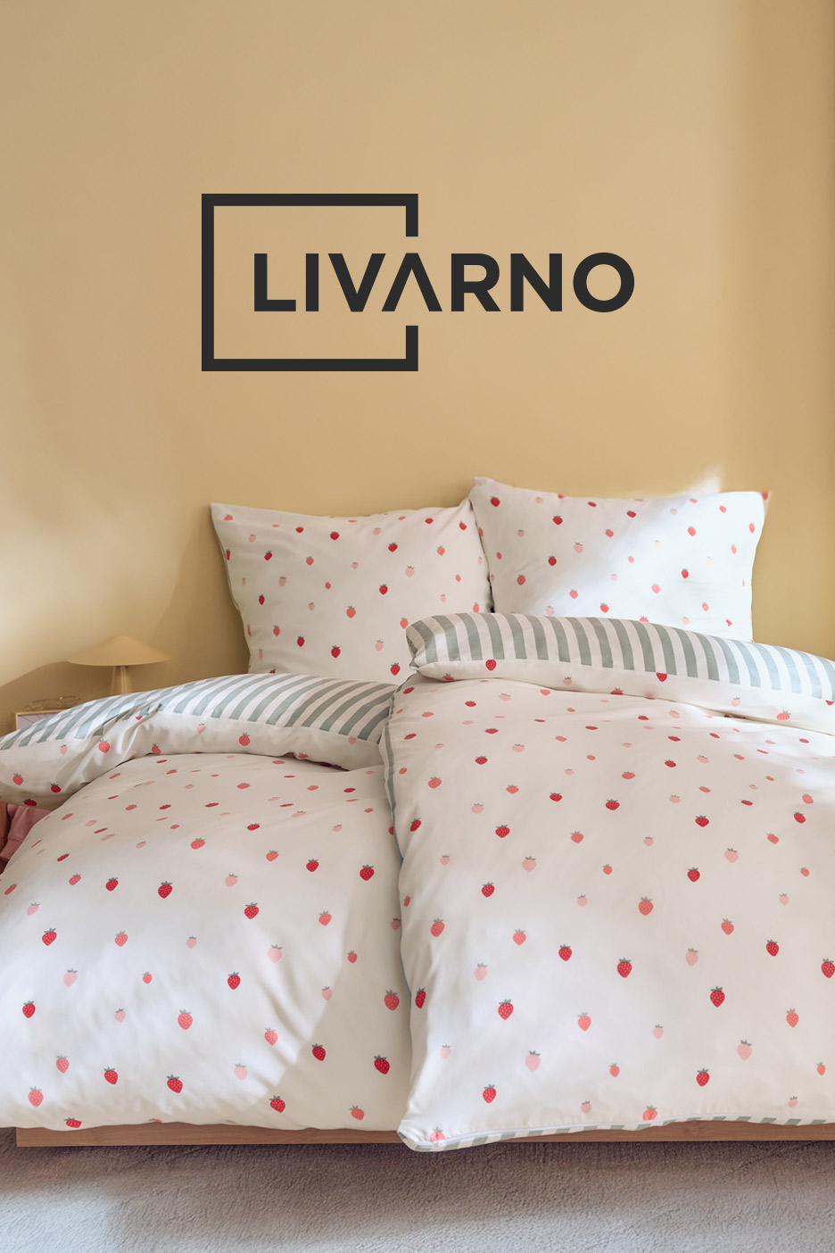Bed with white duvet cover and pillows featuring a strawberry pattern, and a striped pillow.