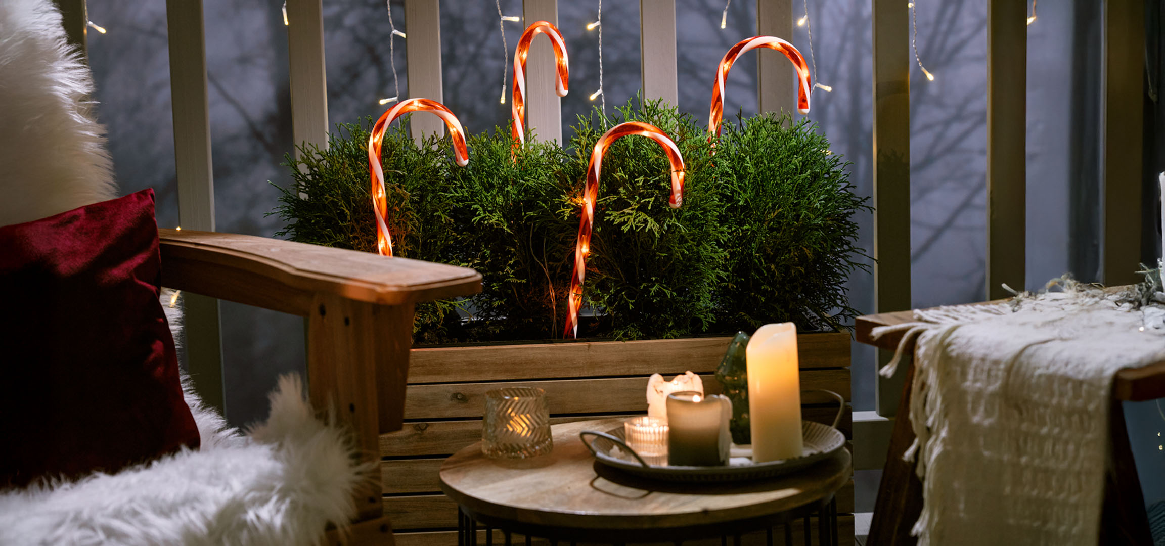 Christmas decorated balcony with a chair, candles, and candy canes.