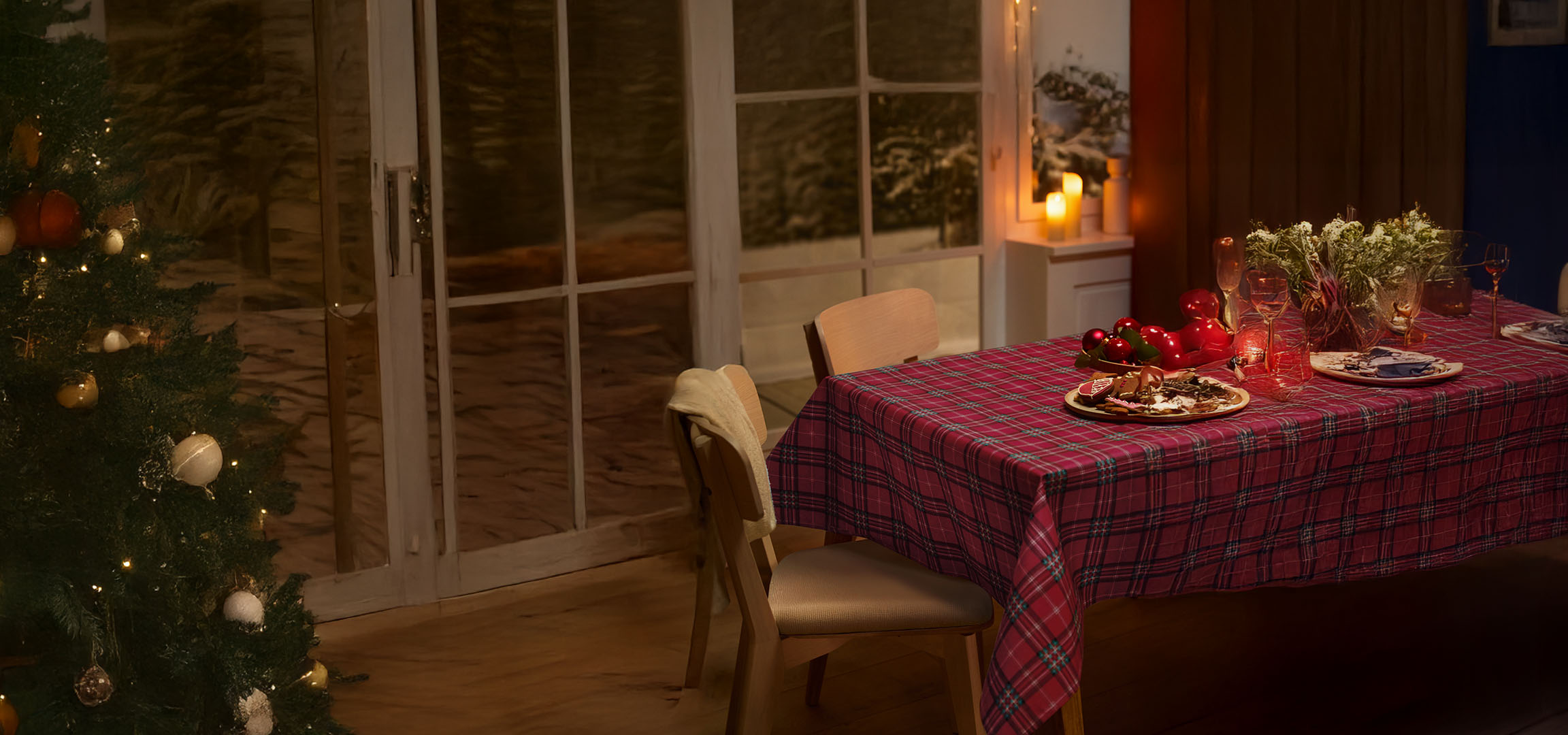Christmas tree and festive table set with plaid tablecloth, gingerbread, and Christmas decorations.