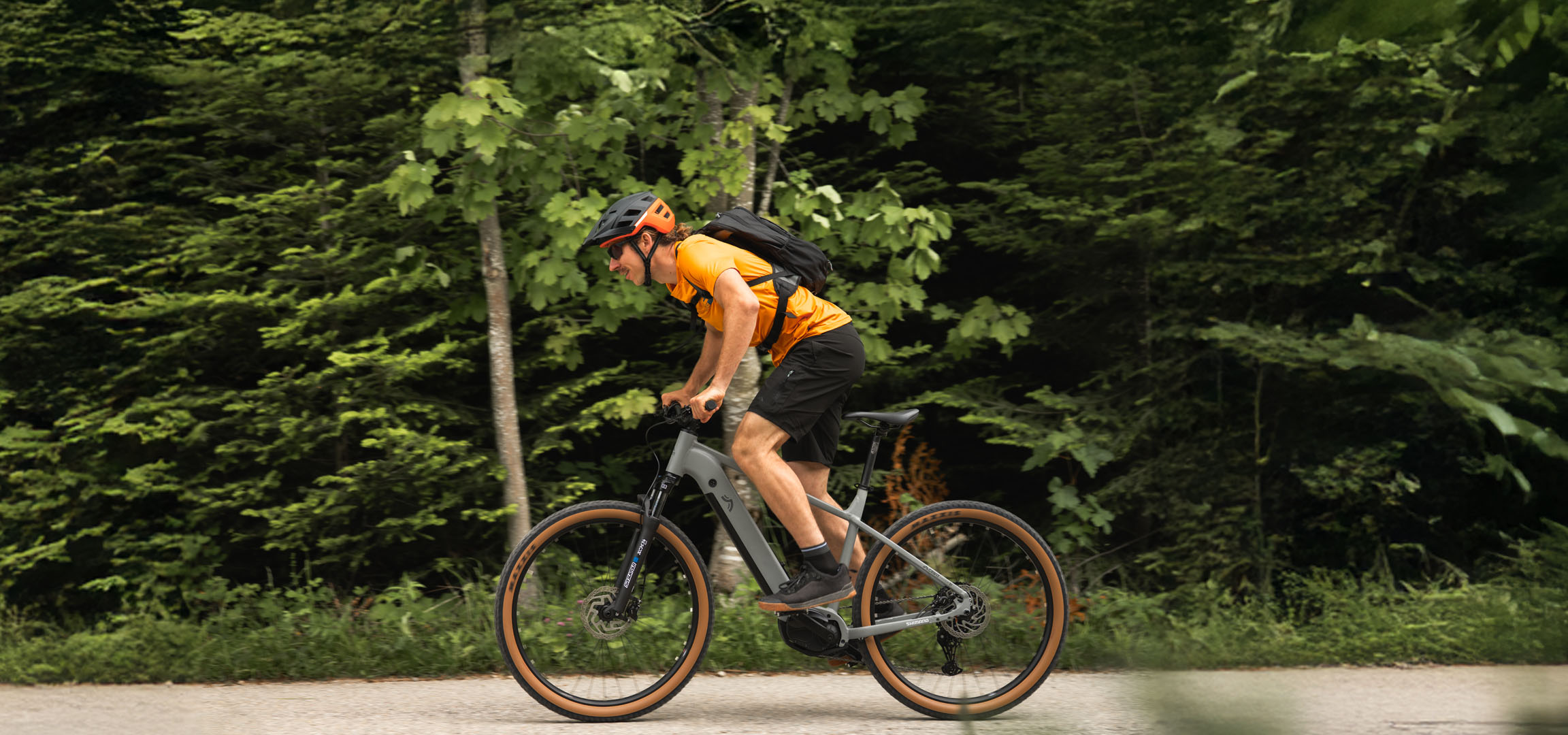 A man rides a Cube e-bike on a forest trail.