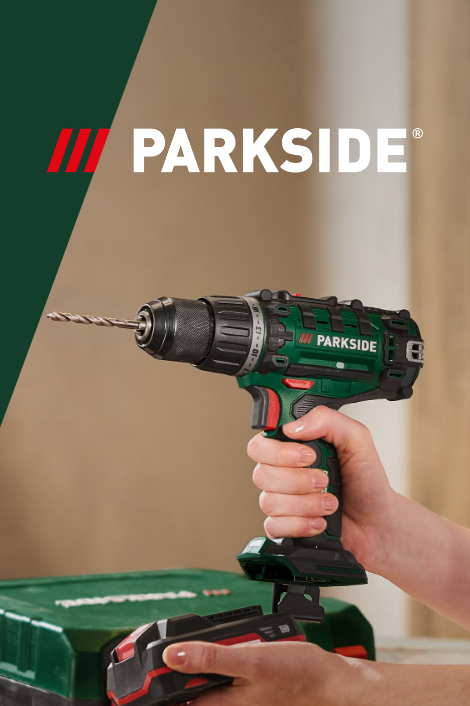 Cordless drill with a drill bit, held by a hand, with a battery pack and tool case.