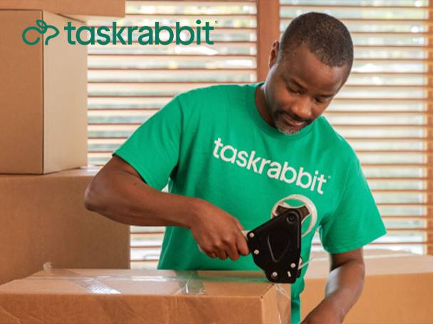 A TaskRabbit worker prepares packages for delivery, using a tape dispenser.