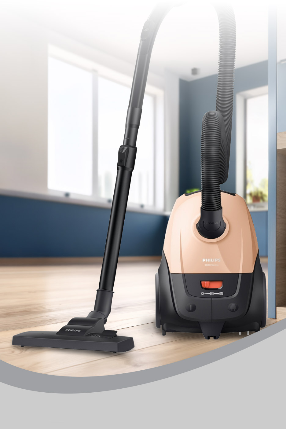 A peach and black canister vacuum cleaner with its hose and floor nozzle on a wooden floor.