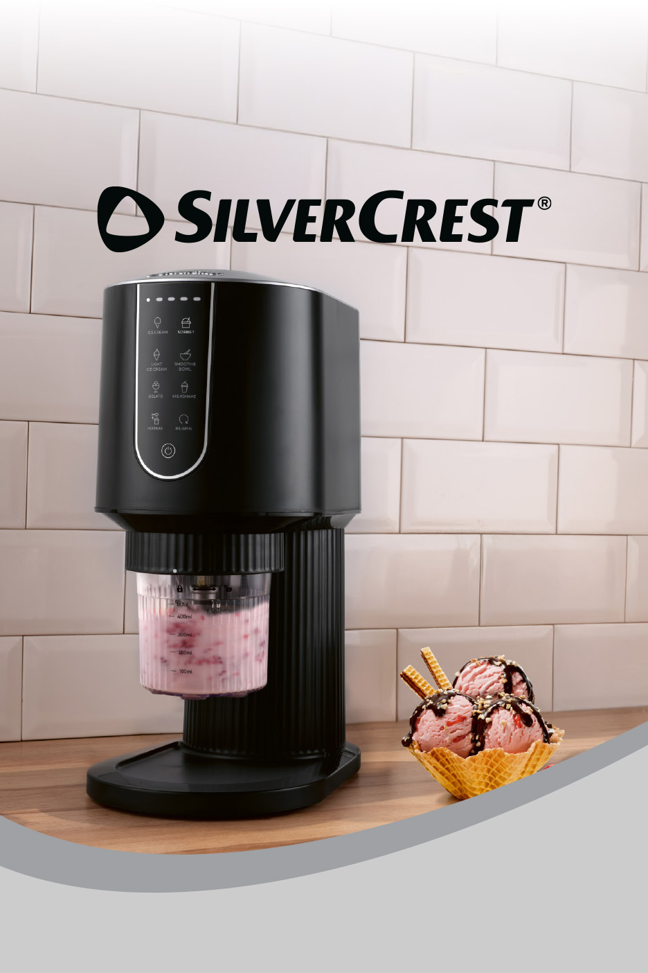 Black ice cream maker on a wooden counter with a bowl of strawberry ice cream.