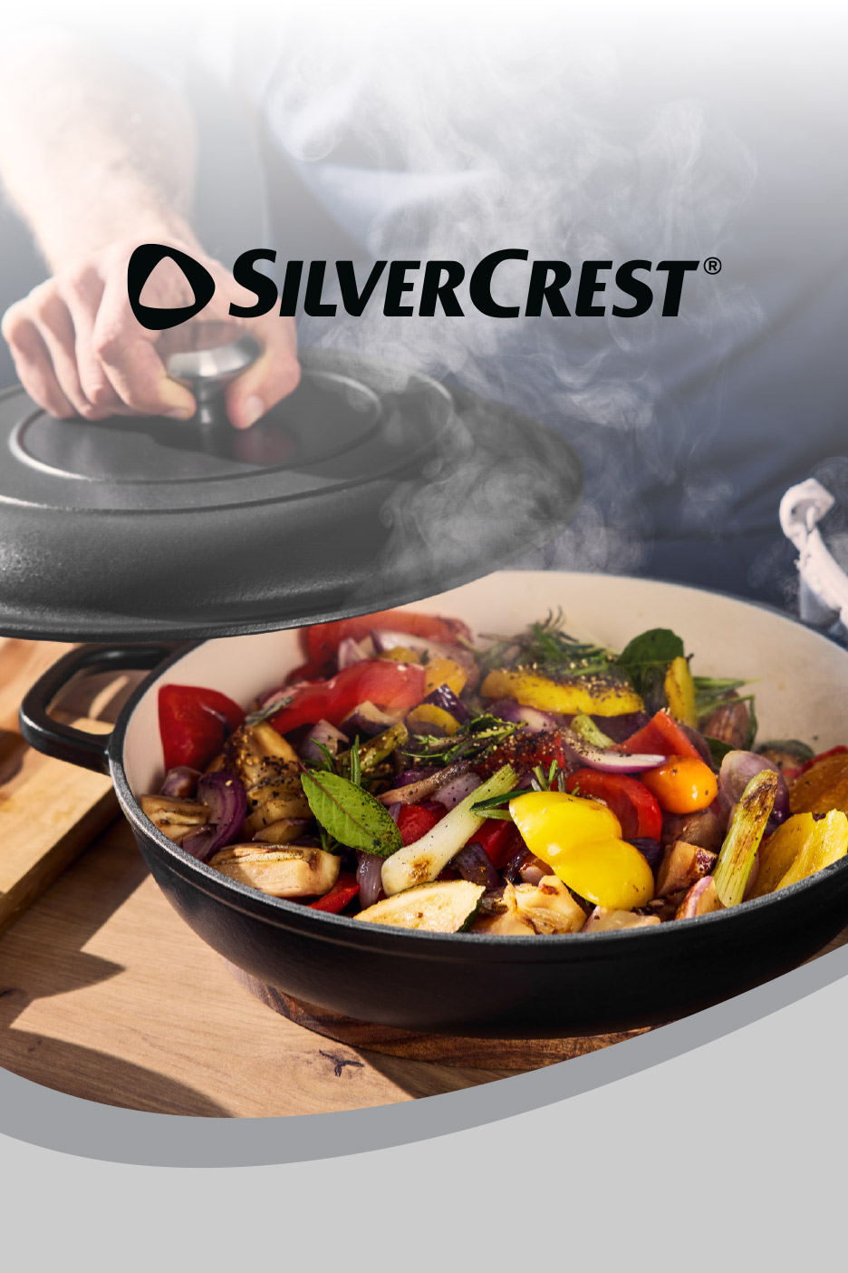 A person lifting the lid off a black cast iron pot filled with colorful roasted vegetables.