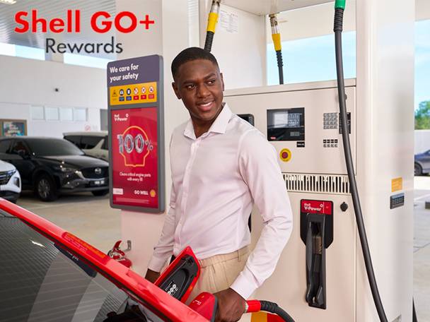 Man fueling car at a gas station, with a rewards sign in the background.