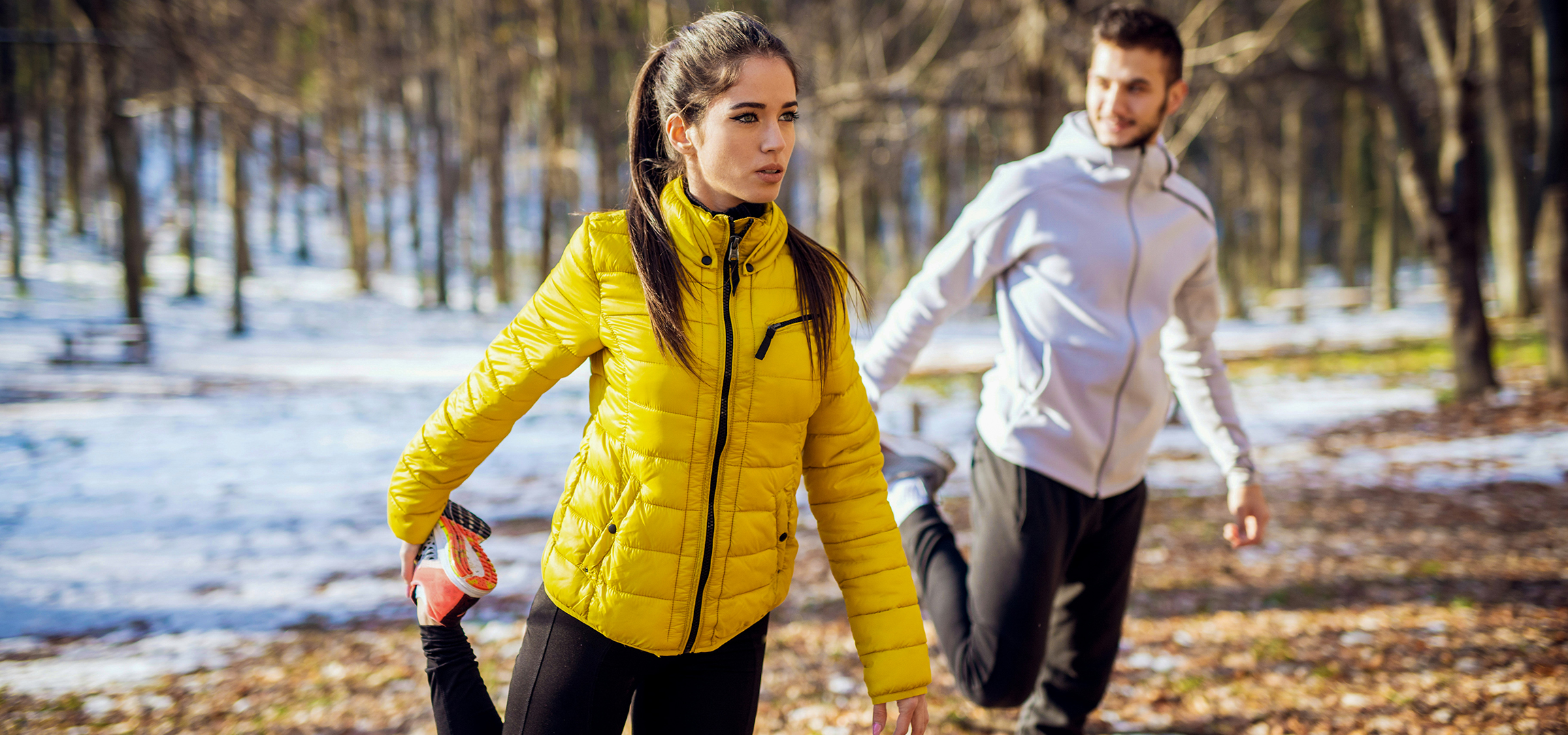 Two people in winter activewear, a woman in a yellow jacket and a man in a white jacket.