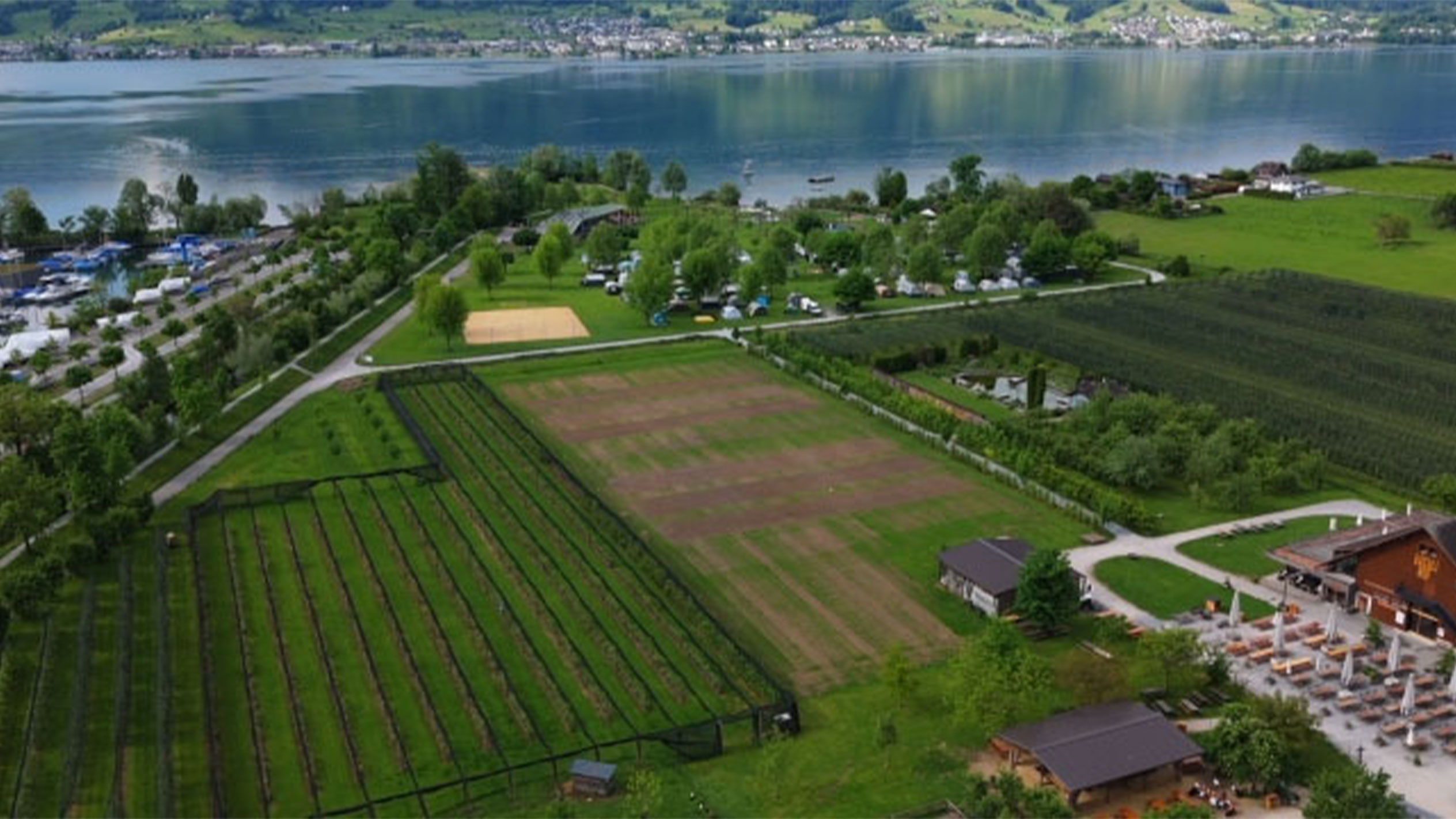Aerial view of a lakeside campground with gardens and a restaurant.