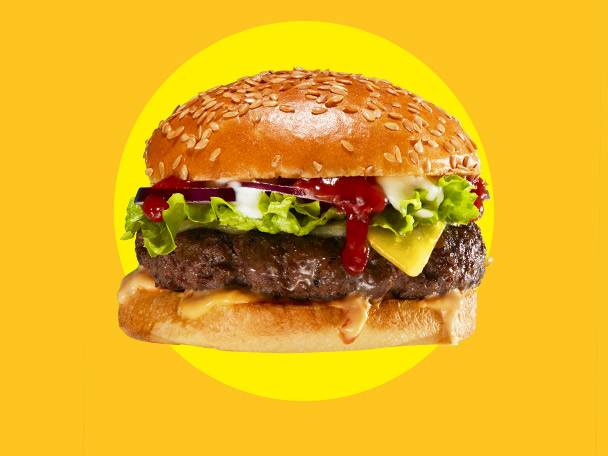 A delicious burger with cheese, lettuce, onion, and ketchup on a sesame bun, on a yellow background.