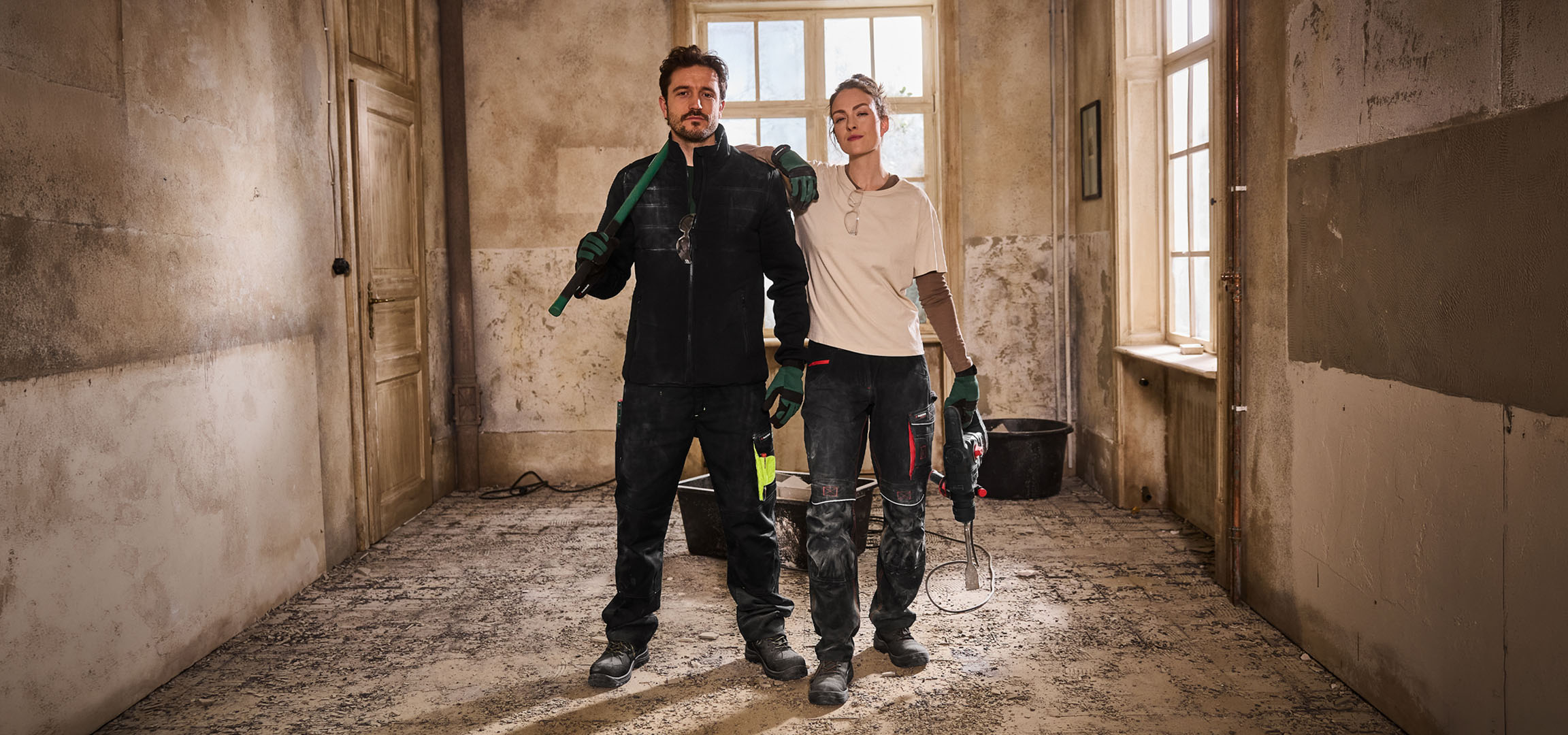 Two construction workers in workwear with tools on a construction site.