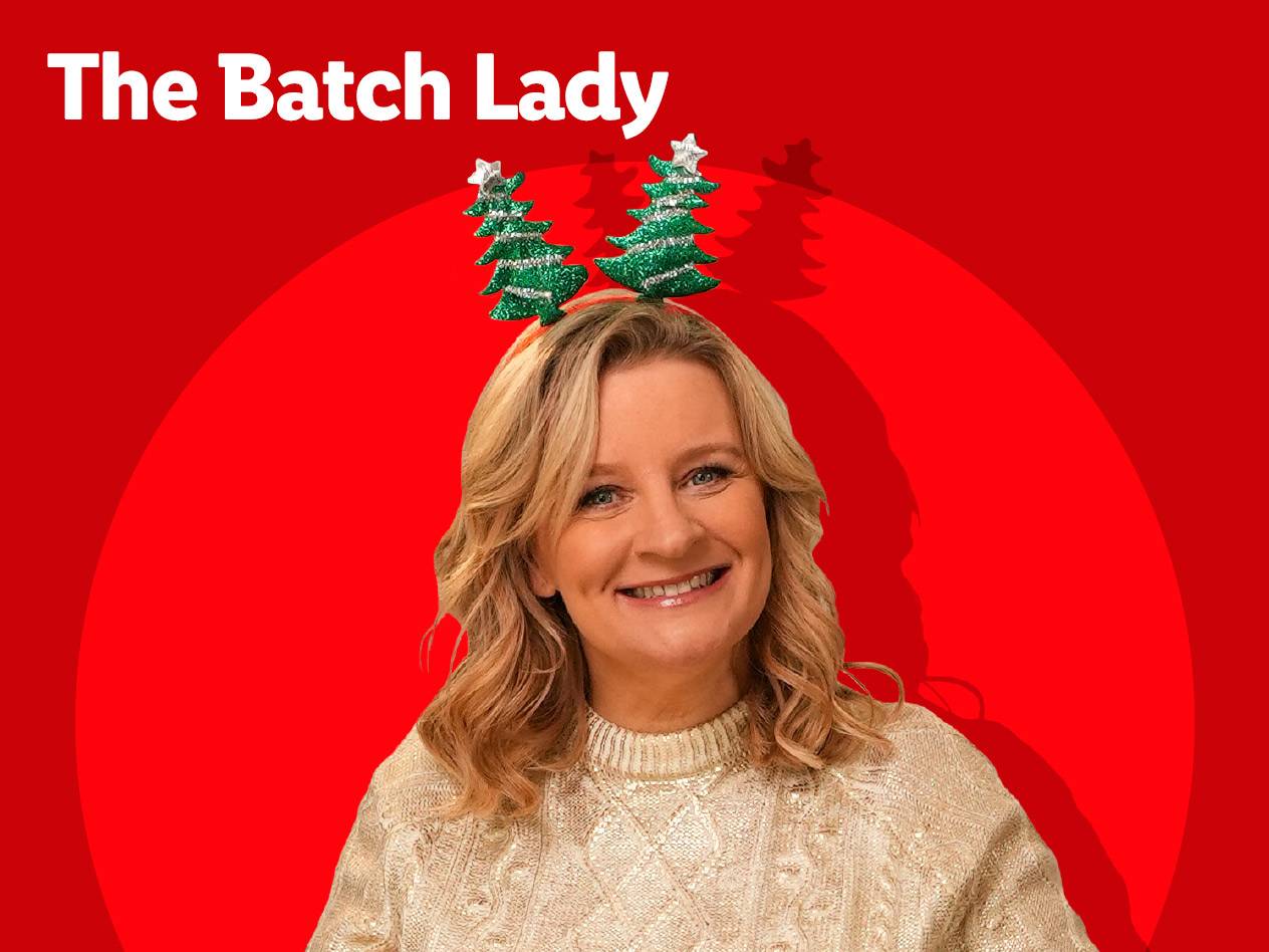 A smiling woman wearing a festive Christmas tree headband and a cream sweater, with 'The Batch Lady' text.