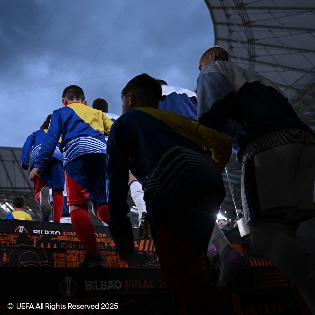 Children and adults walking up stairs, with the UEFA Europa League logo visible.
