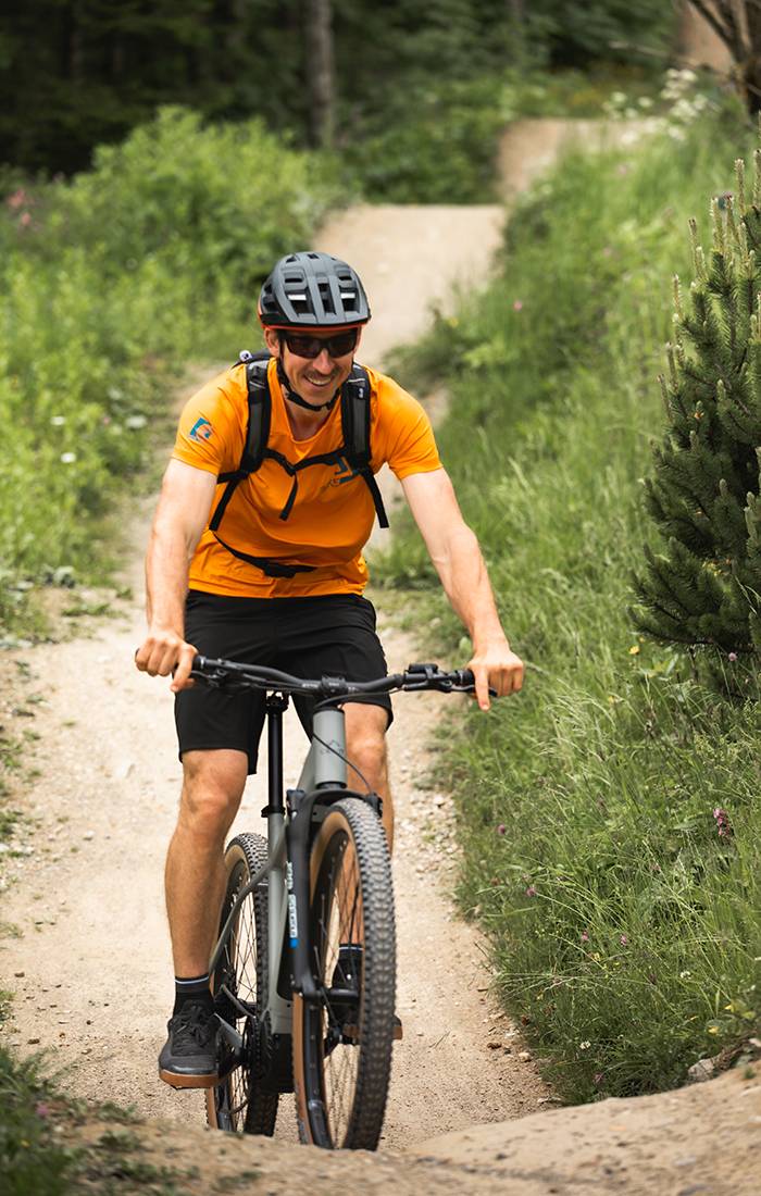 A man smiles while mountain biking on a trail.