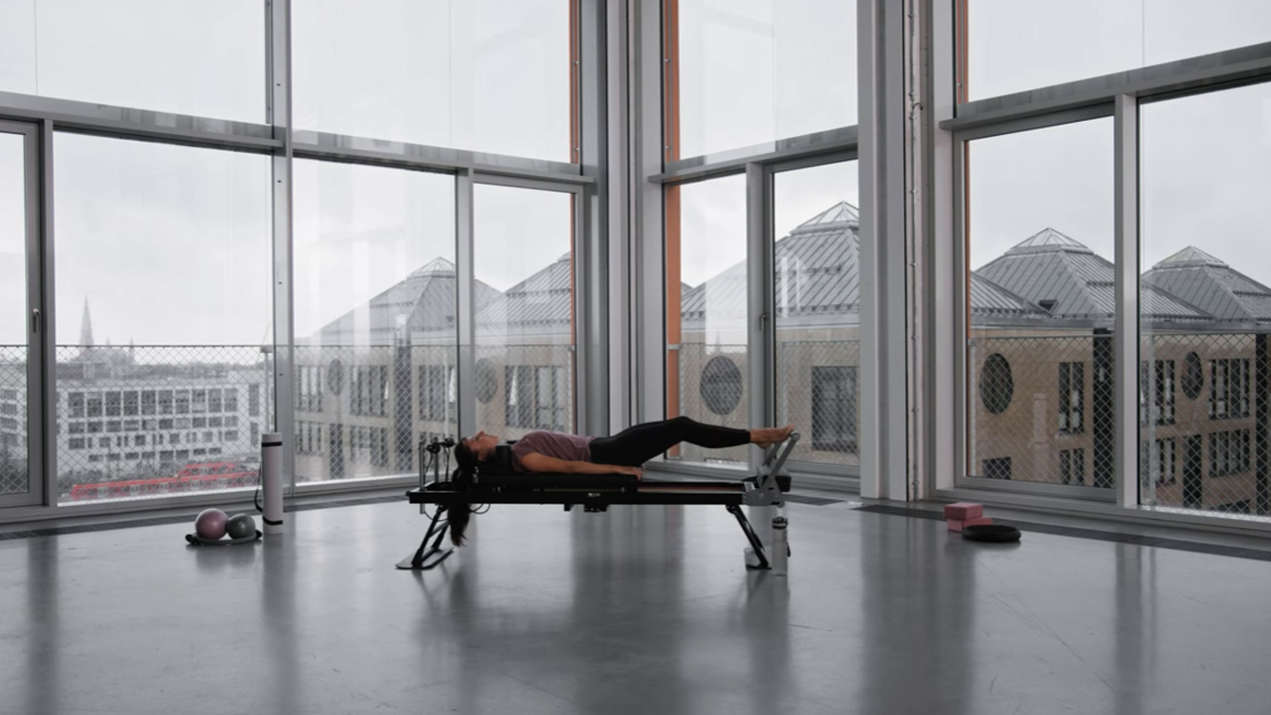 Woman doing Pilates in a modern studio with a city view.